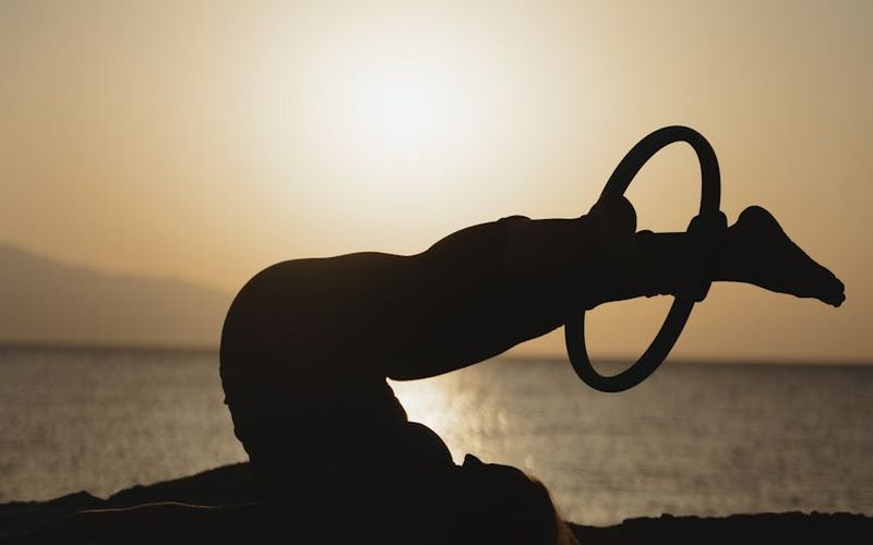 Person doing sun salutation yoga pose outdoors.